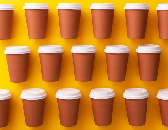 Three rows of disposable coffee cups on yellow background
