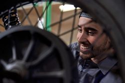 Cheerful male technician examining motorbike