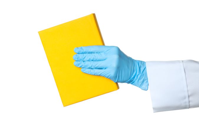 Doctors hand in glove holds book, isolated on light background