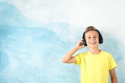 Boy with headphones against color background, space for text