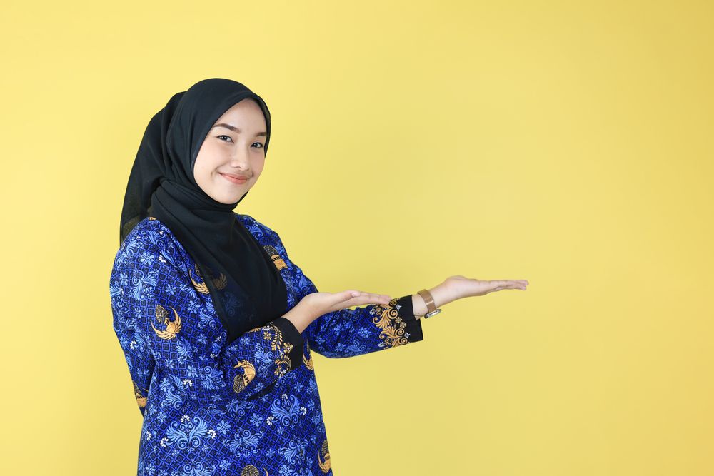 Female Indonesian ASN Wearing Hijab and Korpri Uniform Pointing on the Left Side