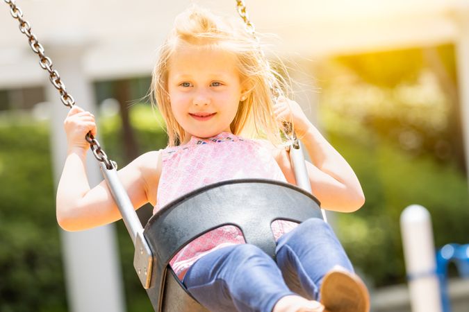 Young Girl Having Fun On The Swings At The Playground