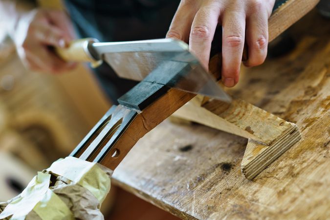 Man scoring wood for guitar on workbench in luthier workshop