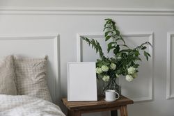 Bedside table with mockup frame next to comfortable bed