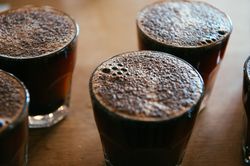 Close up shot of bubbles on top of hot coffee glasses
