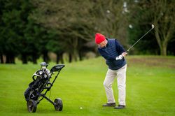 Mature male swinging golf club
