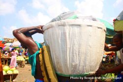 Young man holding a huge baggage on his back standing at street market in Lagos, Nigeria 56Eed0