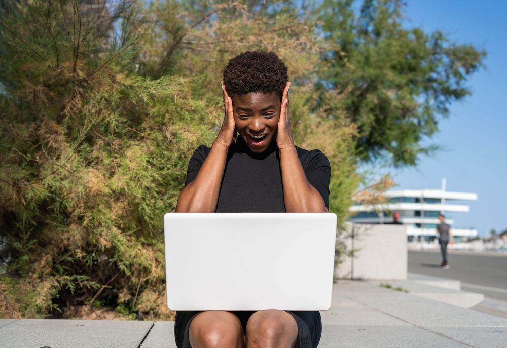Serious female surfing laptop near modern building