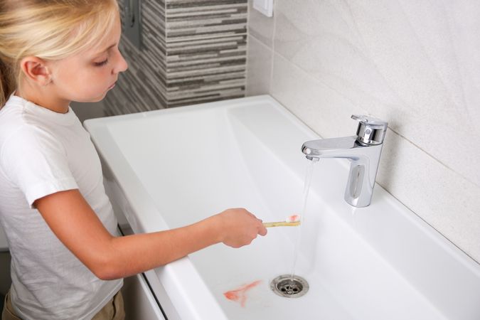 Blood on toothbrush on background of sink. Selective focus on the toothbrush.