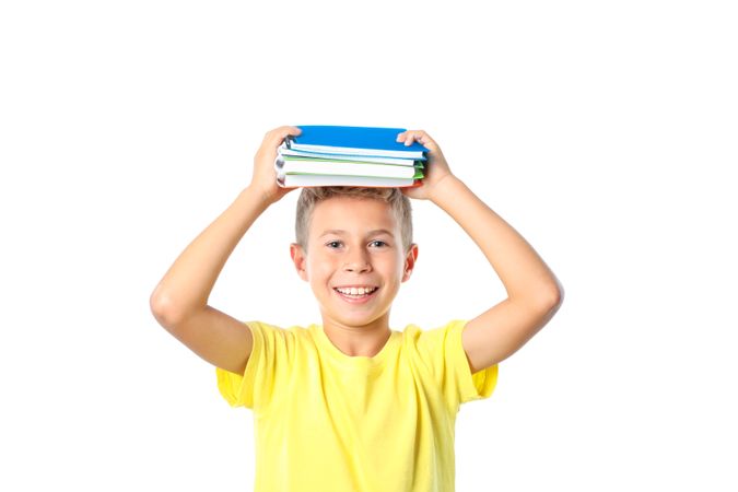Boy in yellow t-shirt with copybooks isolated on blank background
