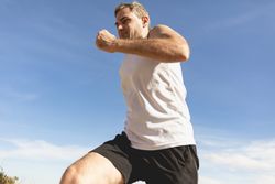 A man with gray hair runs and exercises in the countryside leading a healthy lifestyle