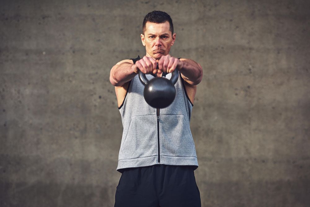 Man lifting kettlebell in concrete space