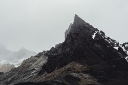 Harsh mountain snowy peak shrouded in fog