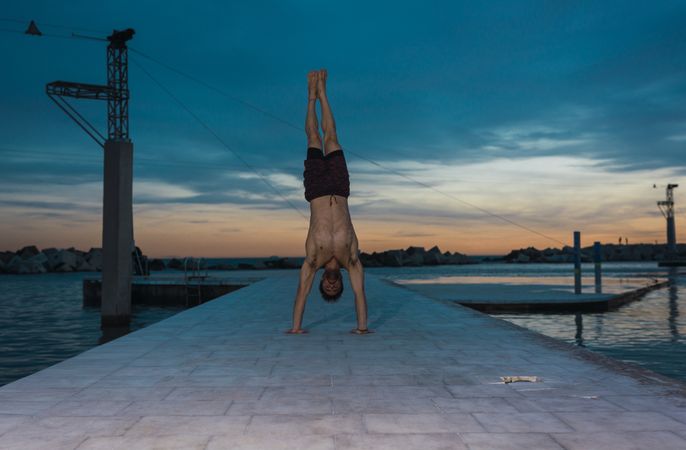 Athletic man balancing on hands on embankment