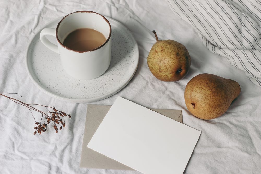 Blank business card mockup and pear fruit on bed sheets