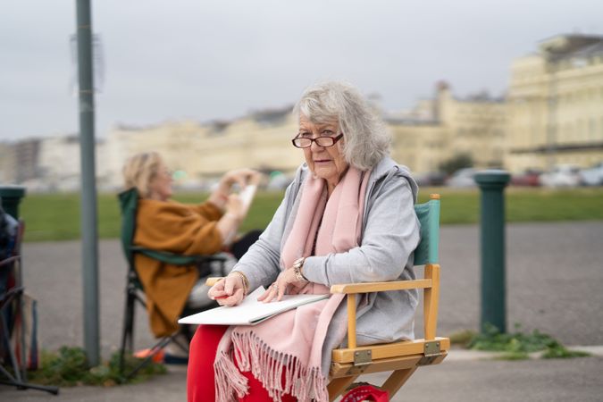 Grey haired woman sitting with drawing board and drawing