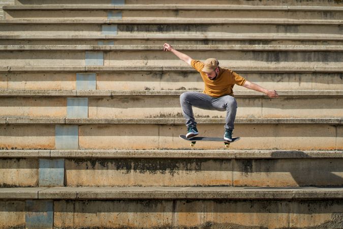 A young man jumping with his skateboard on the bleachers