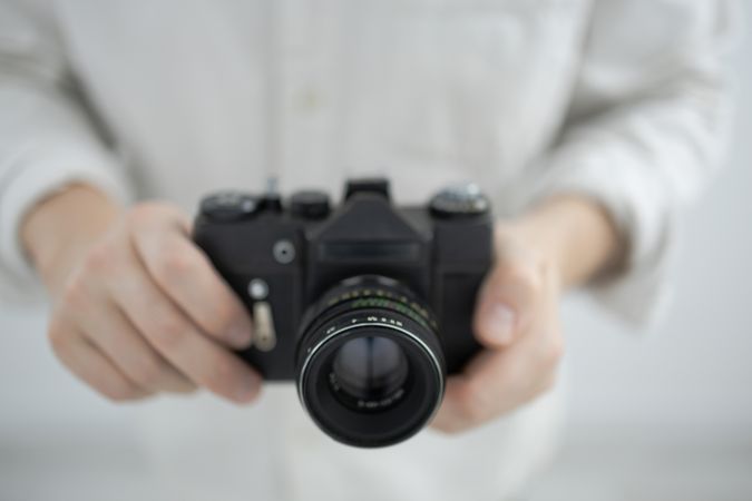 Man holding retro camera on light background