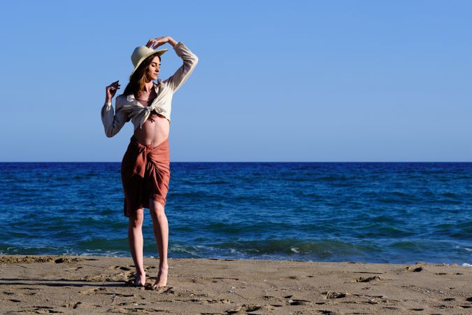 A fashion model with a hat at the beach before sunset
