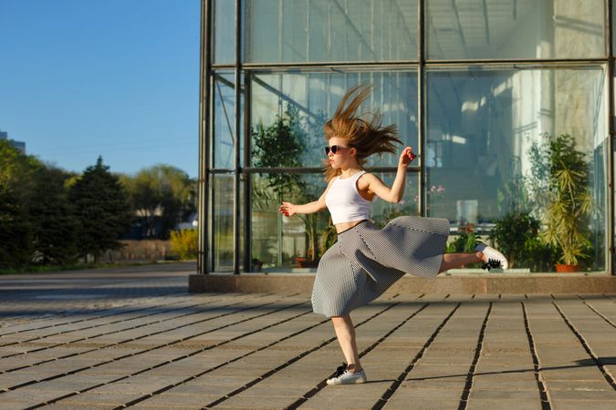Female in skirt joyfully dancing in the sun