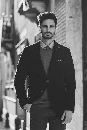 Serious man in the street wearing elegant suit with sun in background, b&w