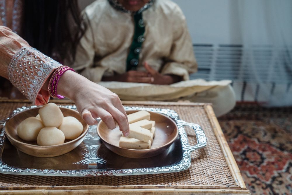 Cropped image of woman taking a bite from Diwali's dessert
