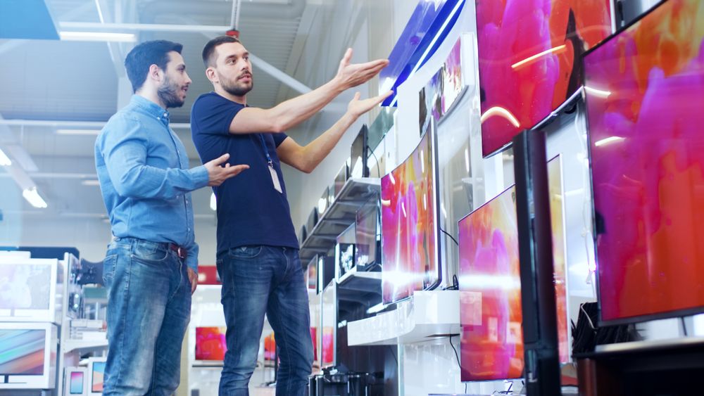 In the Electronics Store Professional Consultant Shows Latest 4K TV's to a Man