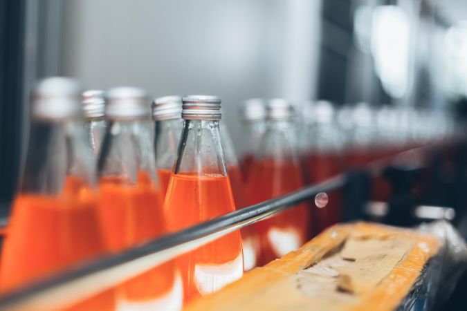 Orange colored soda bottles on conveyor belt in factory