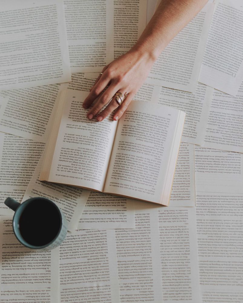 Top view of a hand beside a book a cup of coffee