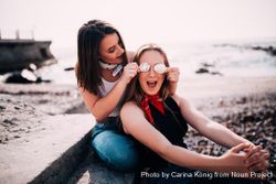 Two young women playing around with seashells on the beach z0gXe5