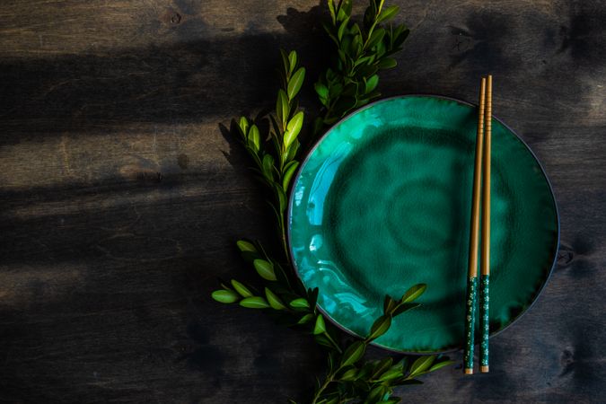 Asian table setting with chopsticks & cherry blossom on teal plate