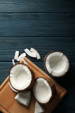 Board with coconut on wooden background, top view