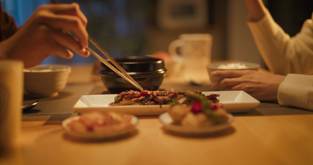 Close Up Portrait of a South Korean Young Couple Eating Food Together in the Kitchen.