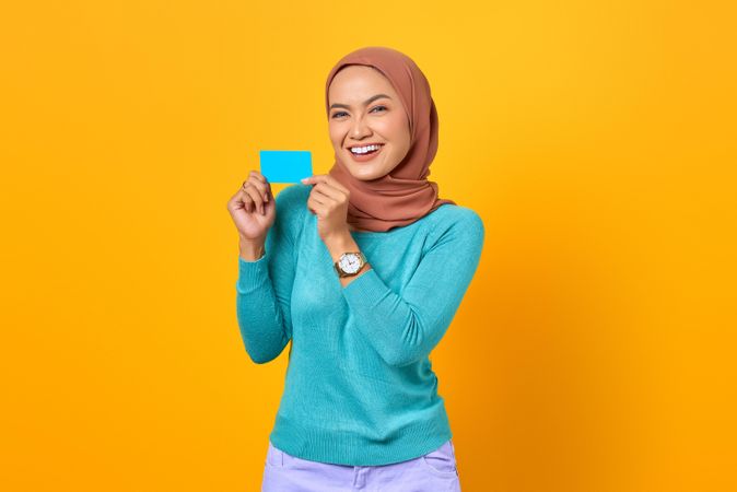 Muslim woman happy and holding credit card with both hands