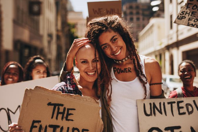 Two woman smiling and embracing at female empowerment protest