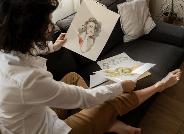 Woman drawing on papers on sofa in room