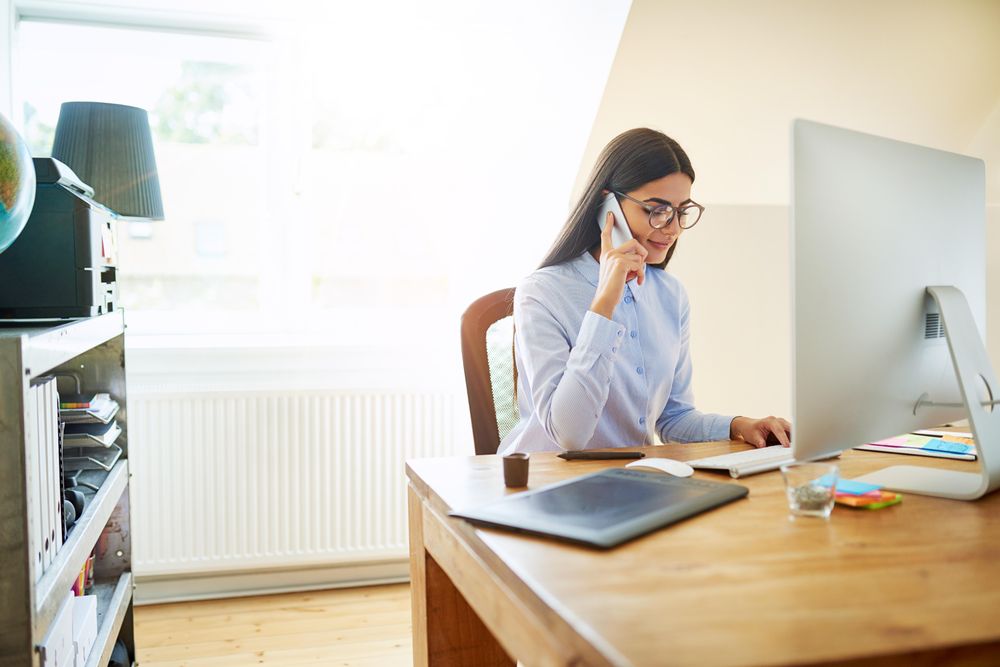 Female businesswoman with her head down taking a phone call in bright office