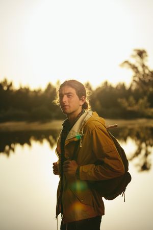 Portrait of a traveler standing beside a lake looking away