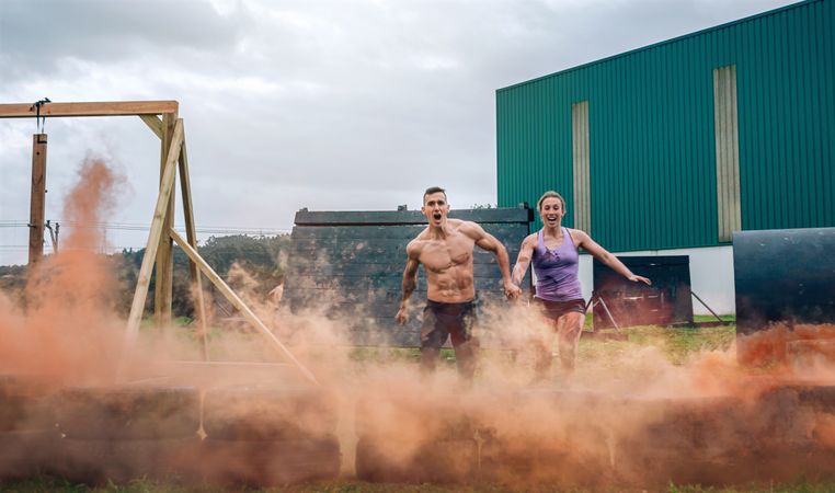 Athletes jumping finish line of an obstacle course