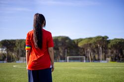 Back of female soccer player with captain armband with LGBT pride flag
