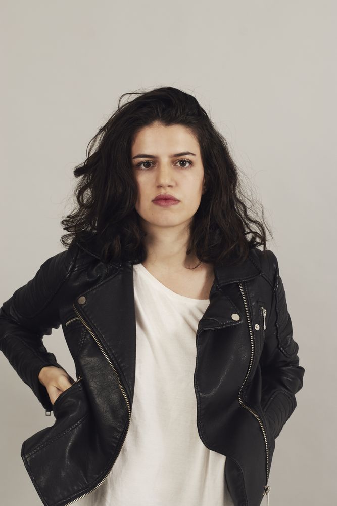 Serious pensive young female wearing leather jacket in studio