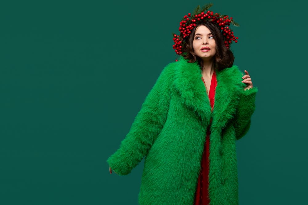 Woman in green faux fur coat and red berry wreath