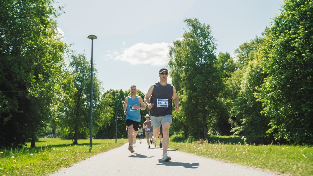Portrait of a Group of People Participating Together in a Marathon and Running Through a Park Trail.
