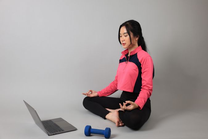 Young Woman Practicing Yoga with Online Lessons in Laptop at Home.