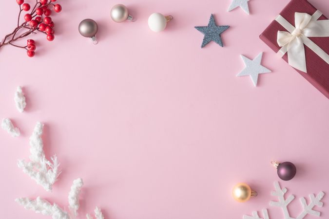 Winter Christmas table layout with presents, decorations, branches on pastel pink background