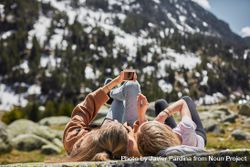 Two young women lay on a flat rock in a mountain scenery 5qknwb