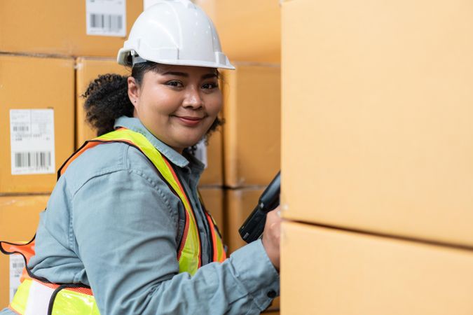 Woman in safety gear working in warehouse full of boxes
