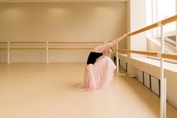 Ballet dancer stretching while seated at barre