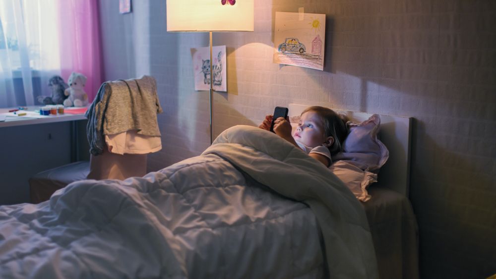 Girl Lies in Her Bed and Watches Cartoons on Smartphone.