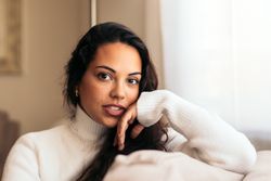 young woman sitting on sofa near window with warm light